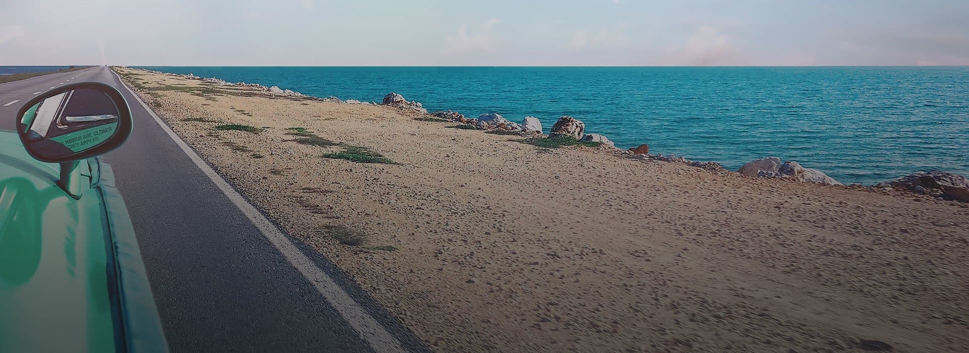 A car on a road with sea on the background